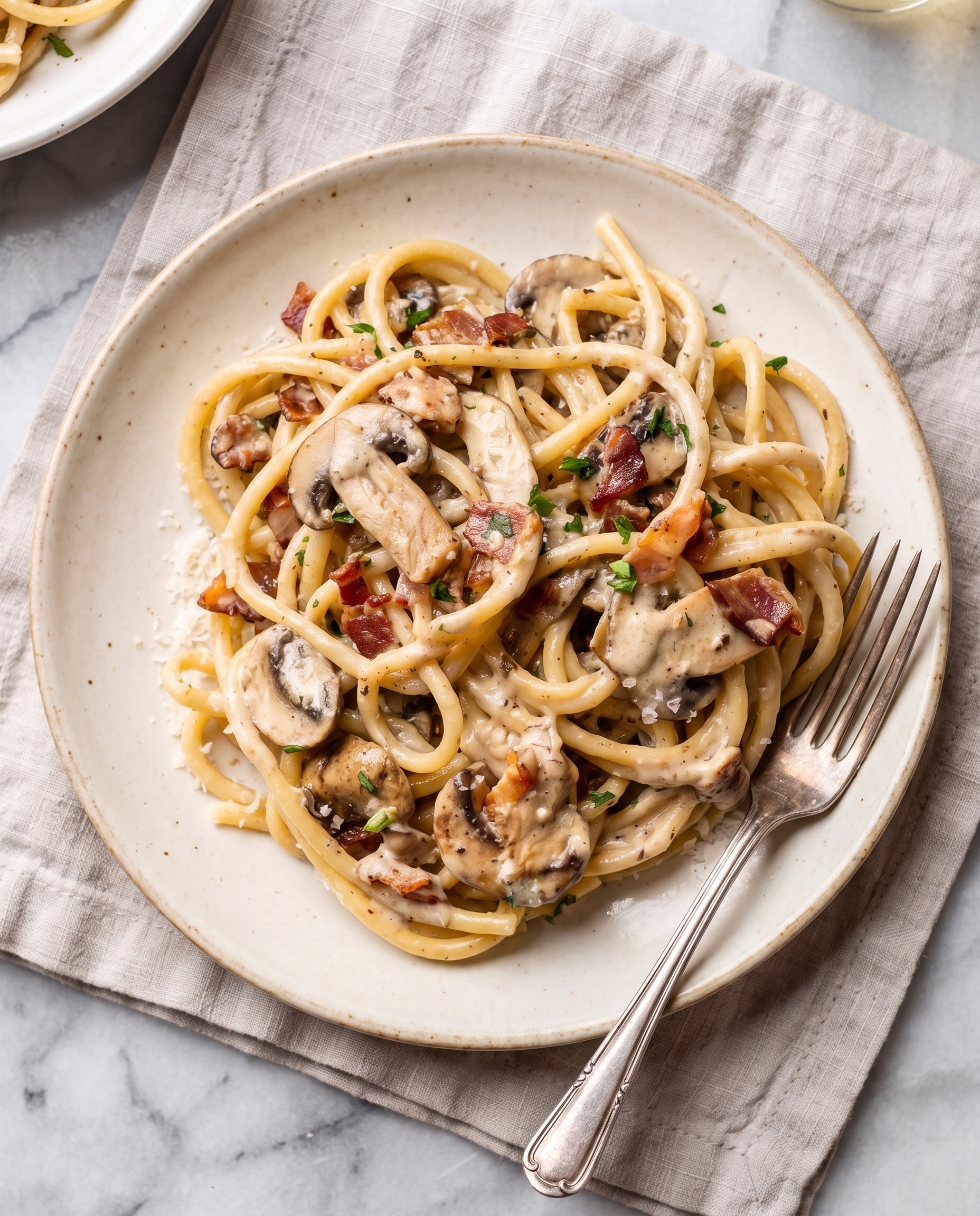Overhead view of creamy bacon mushroom pasta in a wide shallow bowl