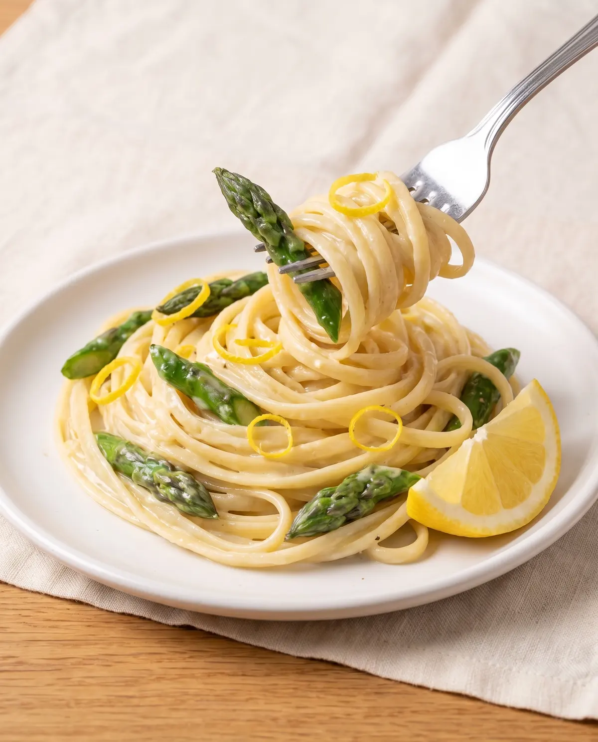 A close-up portion of creamy lemon asparagus pasta on a small white plate