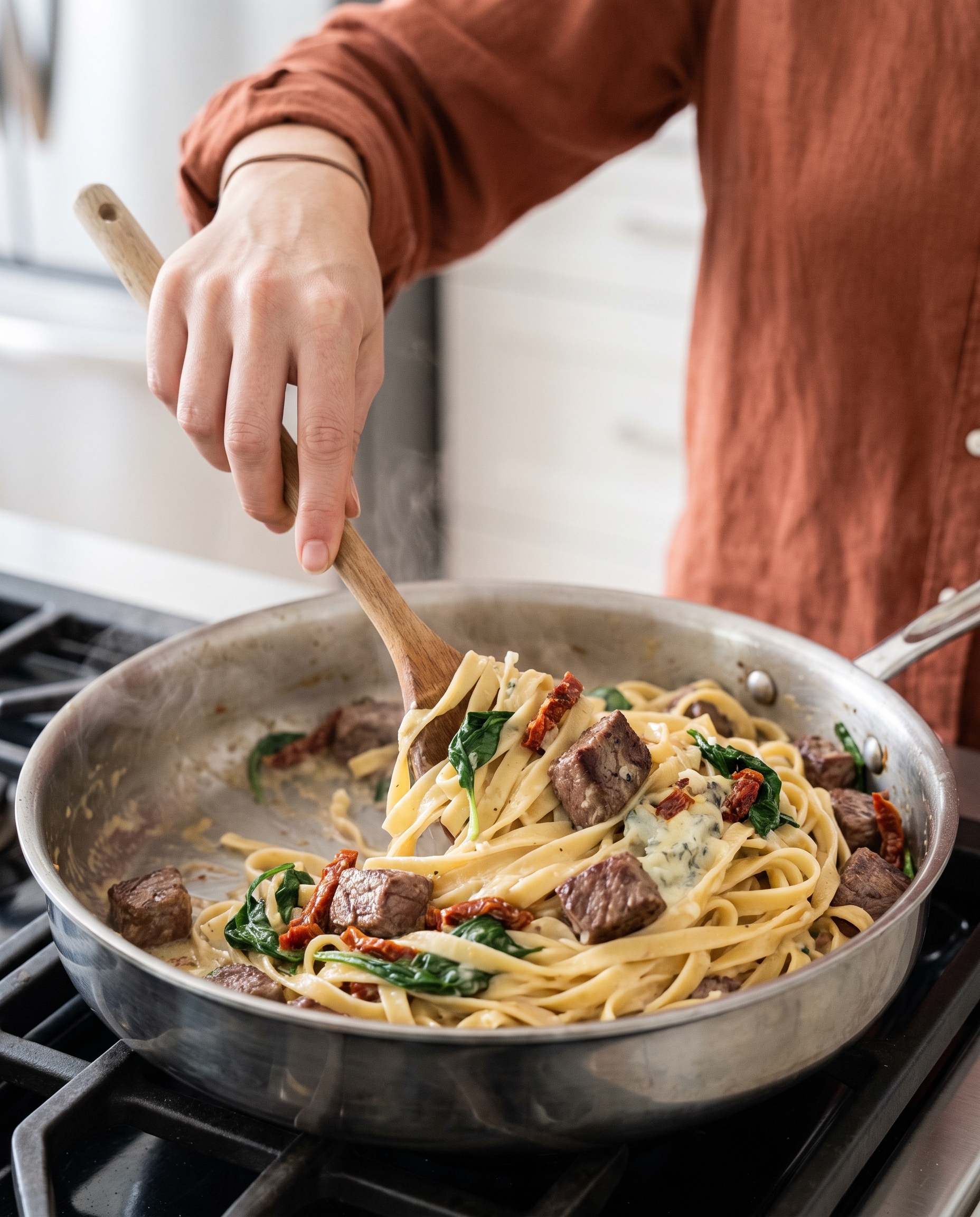 Tossing creamy steak gorgonzola pasta in a skillet