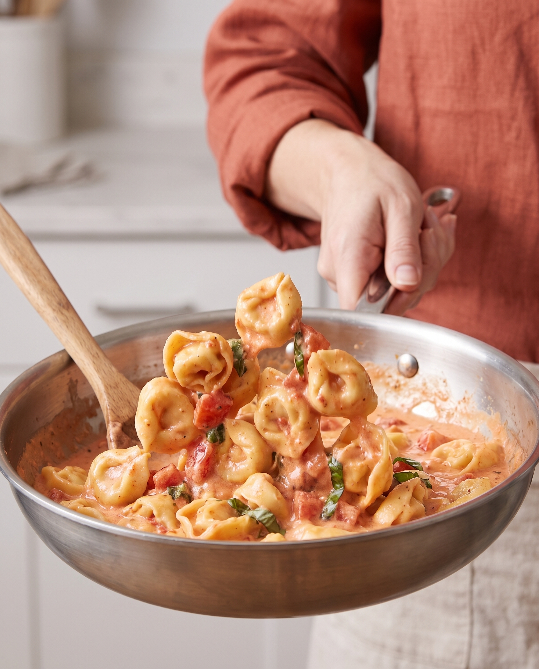 Tossing tortellini in creamy tomato sauce