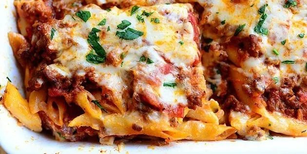A bubbling baked ziti in a large casserole dish, golden brown cheese on top, with fresh parsley
