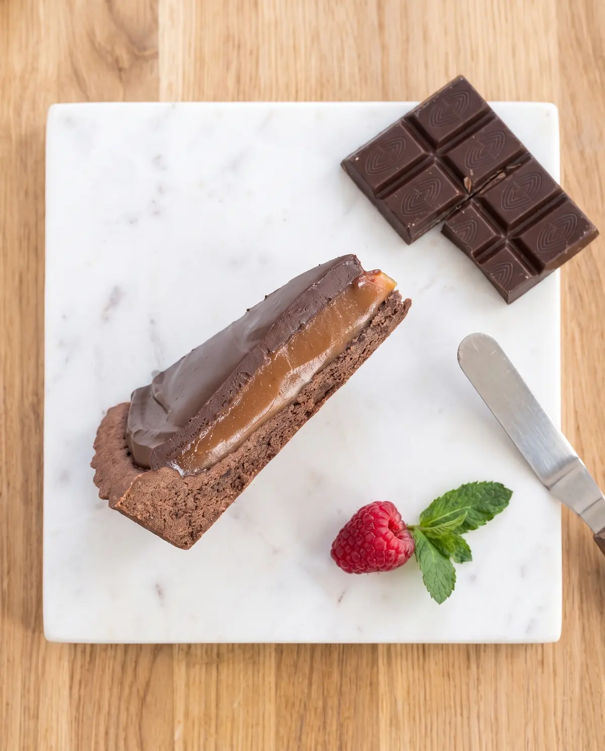 Chocolate caramel tart on marble board overhead showing cross-section layers