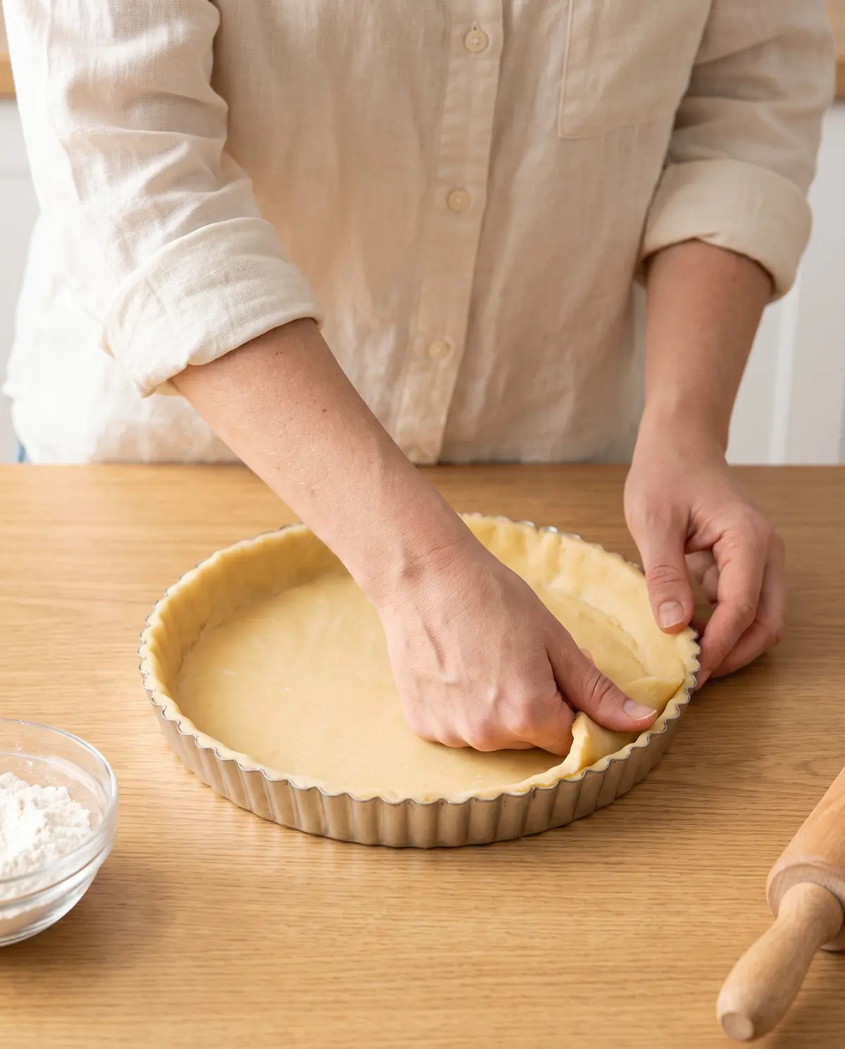 Hands pressing pastry dough into a fluted tart pan