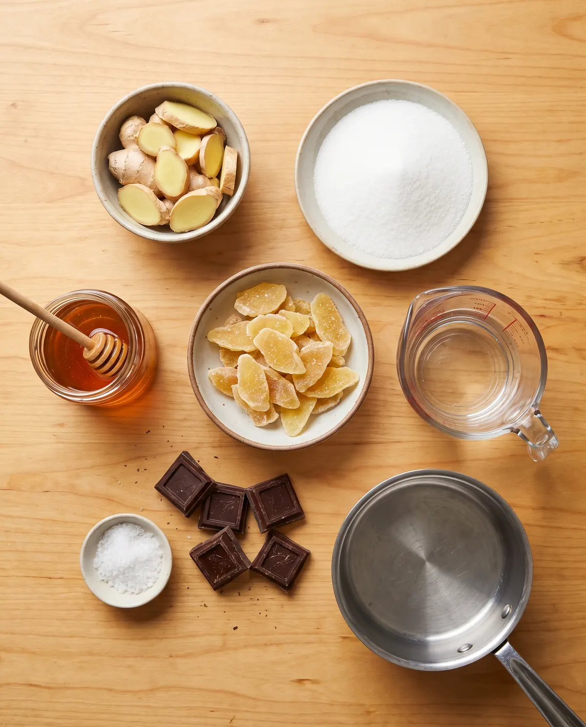 Ingredients for homemade chocolate dipped crystallized ginger arranged on wood surface