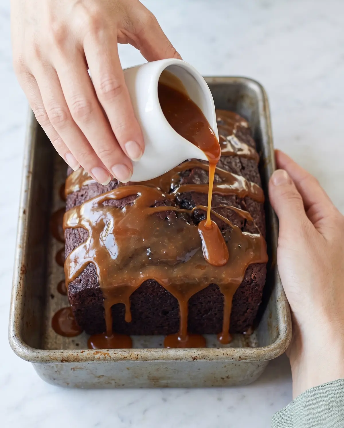 Pouring salted caramel sauce over the freshly baked chocolate Earl Grey loaf cake