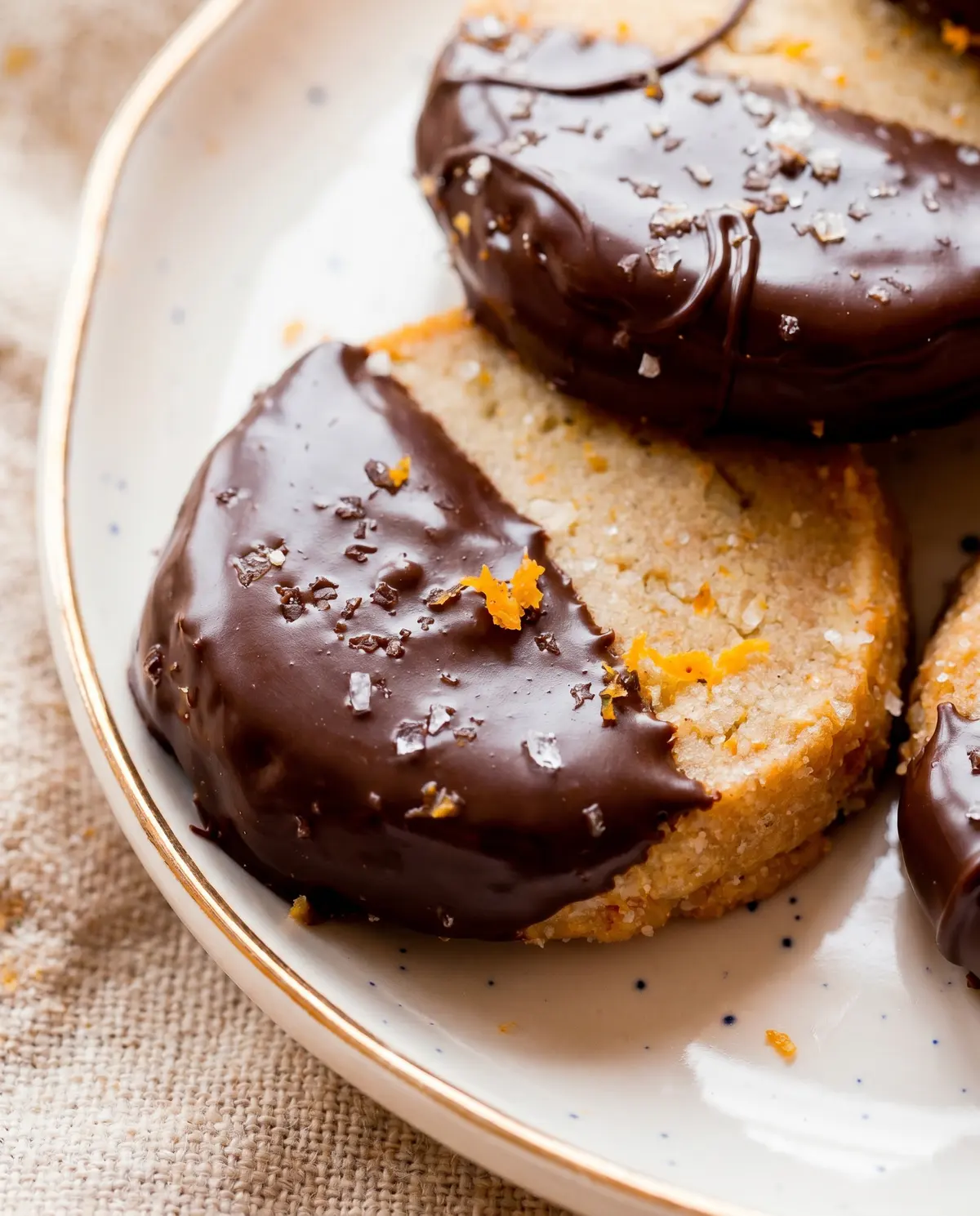 Tight macro close-up of a chocolate orange cookie showing the crackly top, glossy chocolate coating, and orange zest flecks