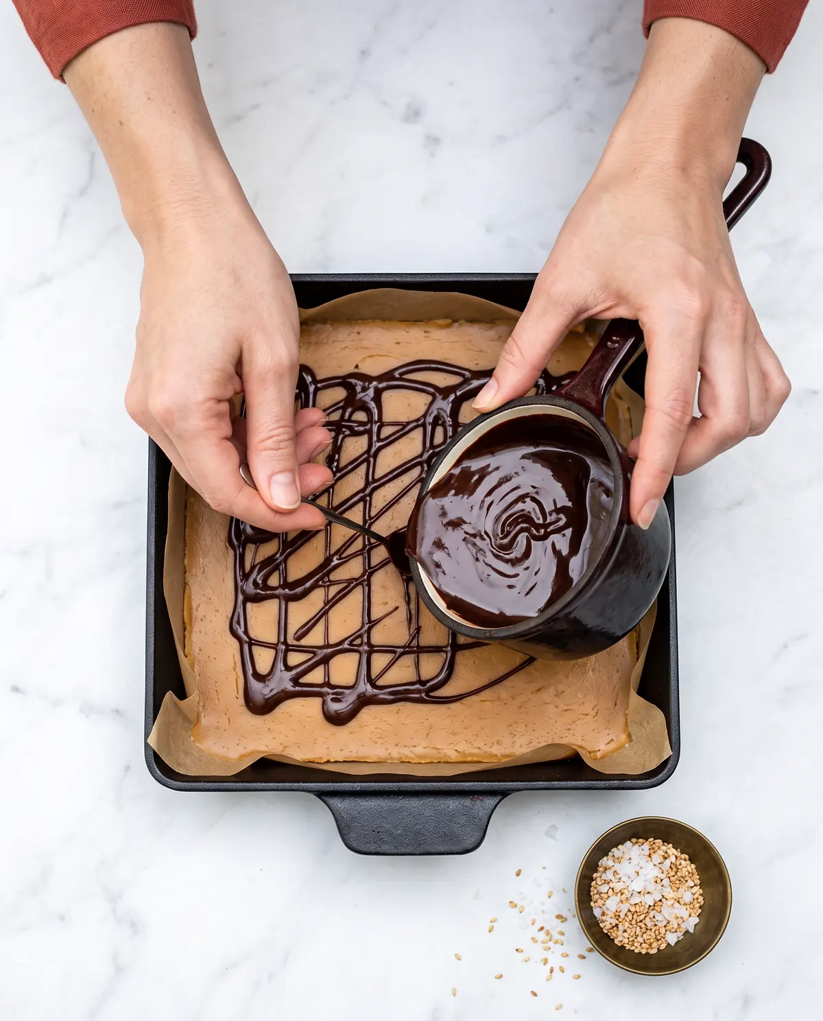 Pouring the chocolate ganache layer over the chilled tahini caramel