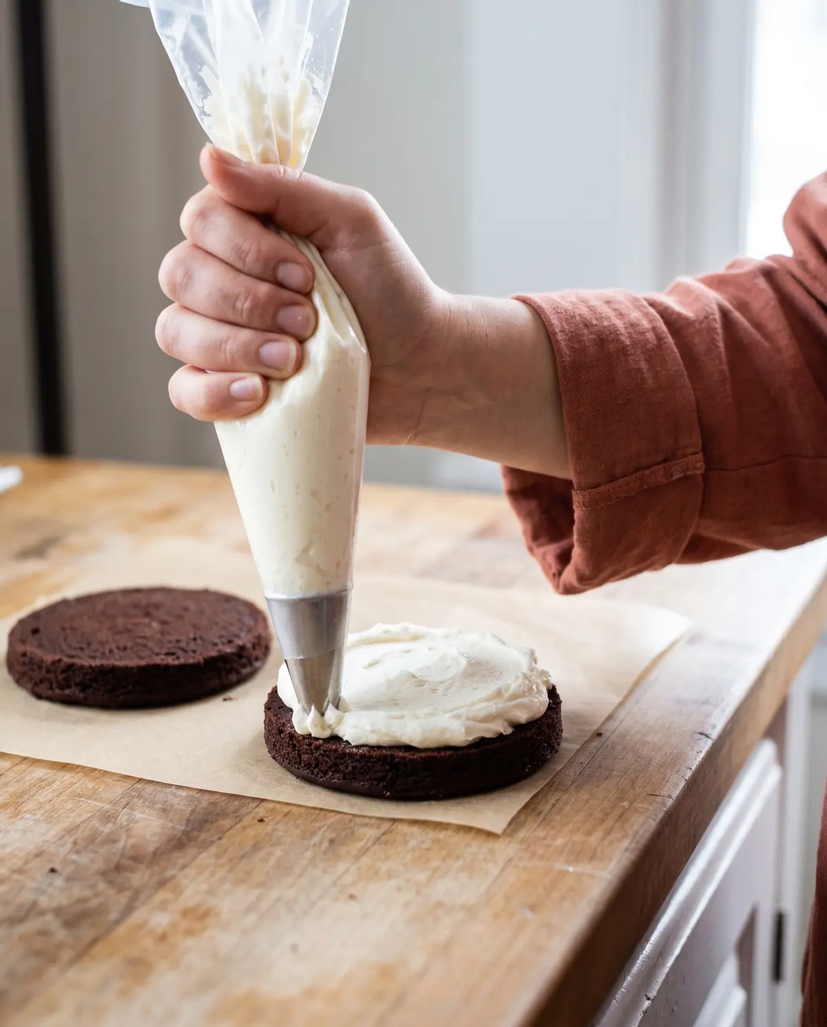 Piping vanilla buttercream onto a chocolate whoopie pie round
