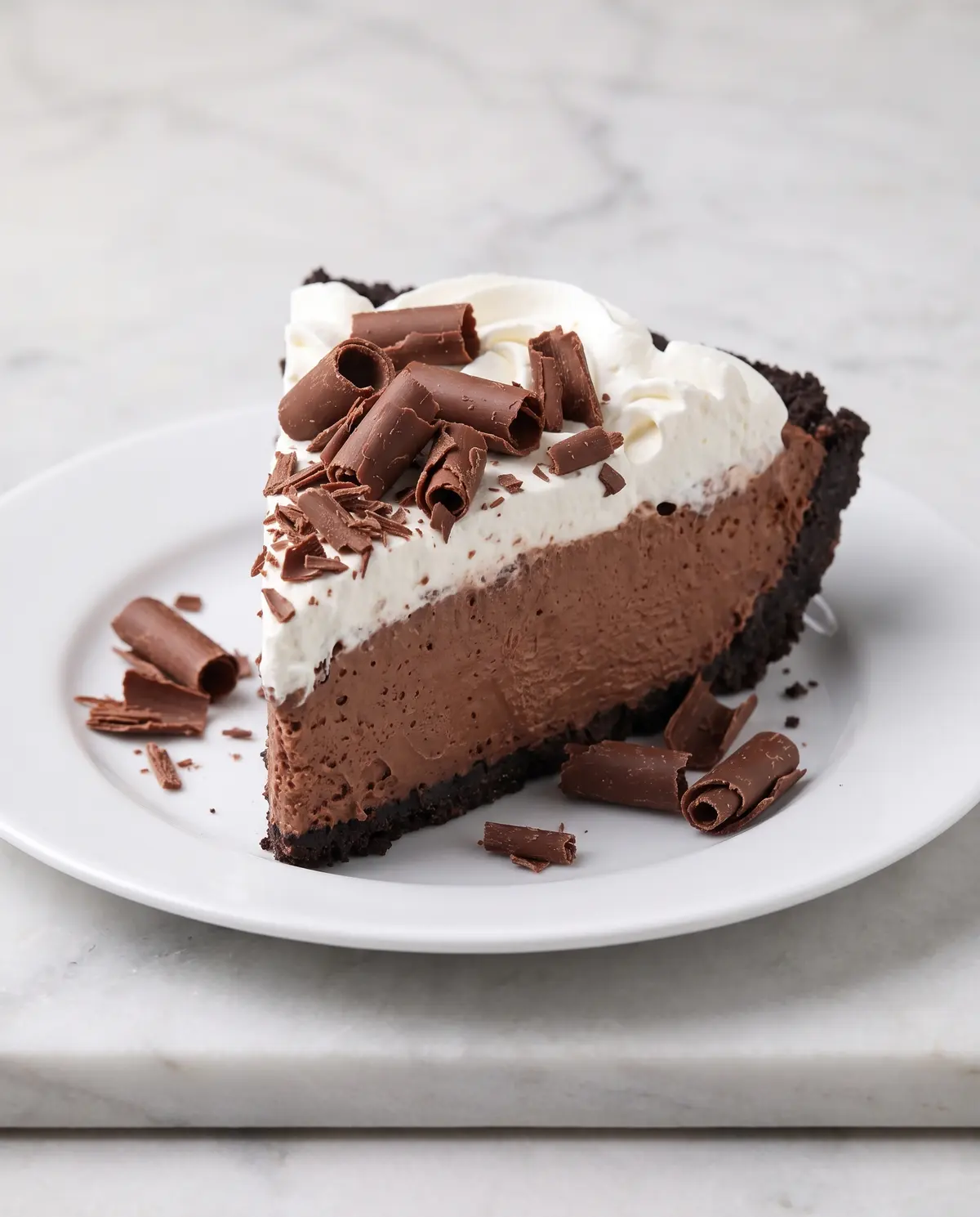Chocolate cream pie from side angle showing full height of whipped cream swirls